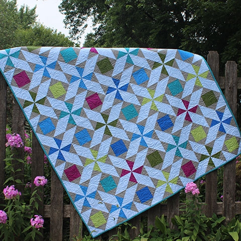 SRQ-Twist-Shout-Quilt SRQ Sticks and Stones Quilt displayed on a fence